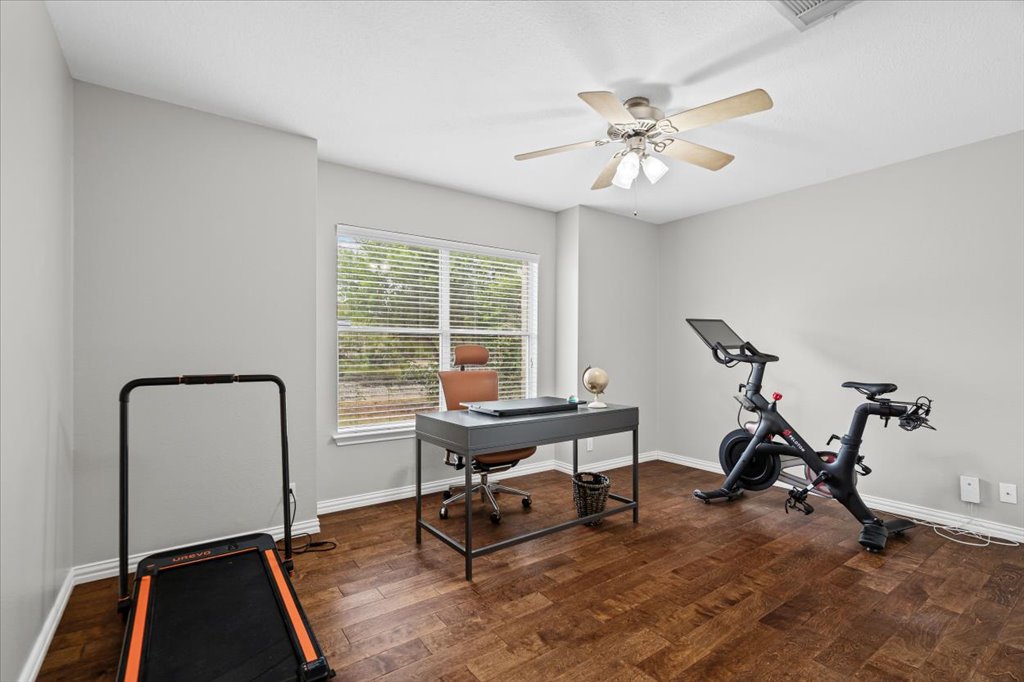 7451 Pusch Ridge Loop Austin, TX 78749 - Photo 22 of 26 Warm wood flooring and abundant natural light create an inviting atmosphere in this versatile bedroom space.