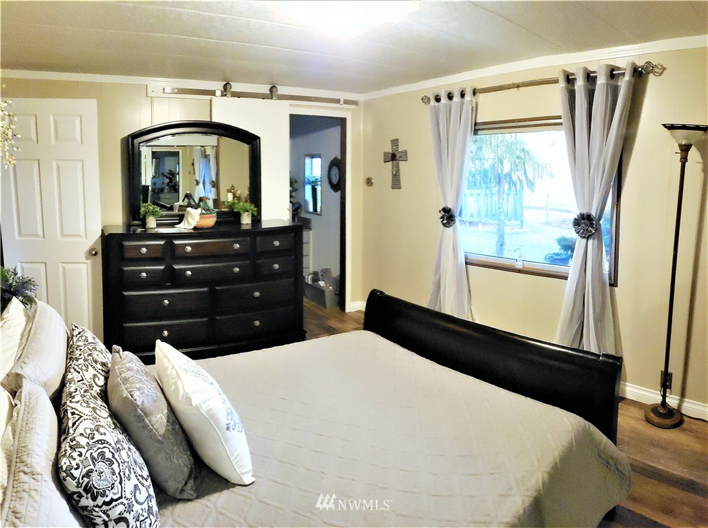 49 Sand Flat Road Omak, WA 98841 - Photo 21 of 40 a bedroom with a bed a mirror on the dresser and a large window