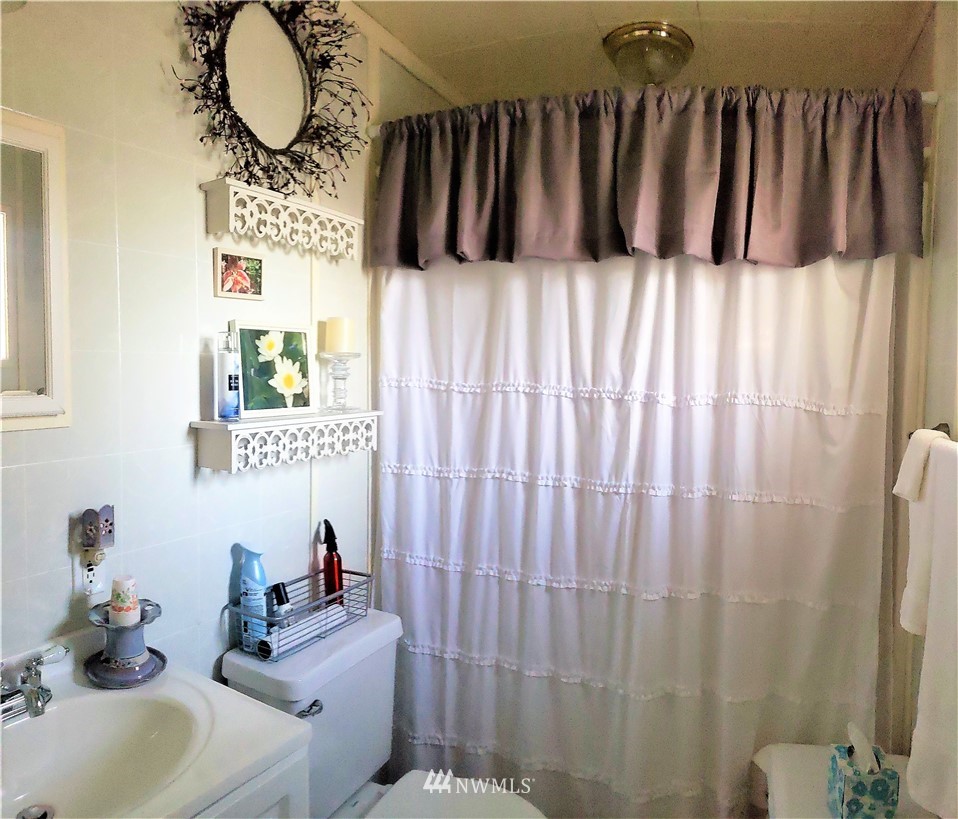 49 Sand Flat Road Omak, WA 98841 - Photo 28 of 40 a bathroom with a sink a mirror and a shower curtain