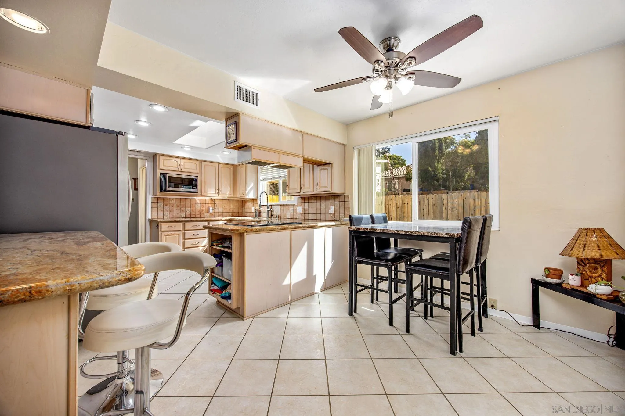 1673 Hidden Mesa Road El Cajon, CA 92019 - Photo 19 of 29 a kitchen with stainless steel appliances kitchen island granite countertop a table chairs and a refrigerator