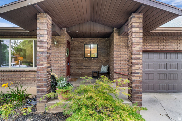 1539 East 450 South Springville, UT 84663 - Photo 5 of 49 Brick exterior with a covered entryway, prominent brick columns, a paneled garage door, and a front door with sidelight