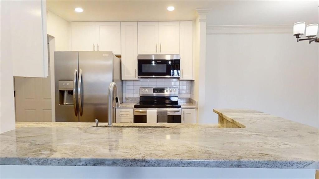300 Johnson Ferry Road, Unit B201 Atlanta, GA 30328 - Photo 13 of 32 a kitchen with granite countertop a refrigerator and a stove top oven