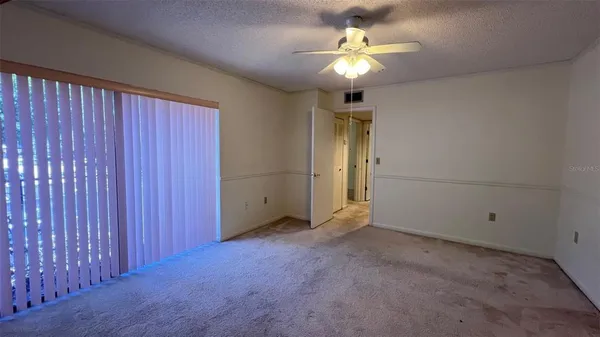an empty room with a chandelier fan and closet
