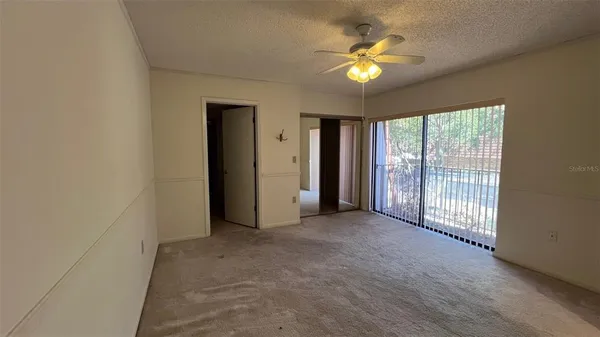 an empty room with closet and a chandelier fan