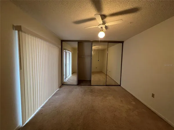 an empty room with a chandelier fan and windows