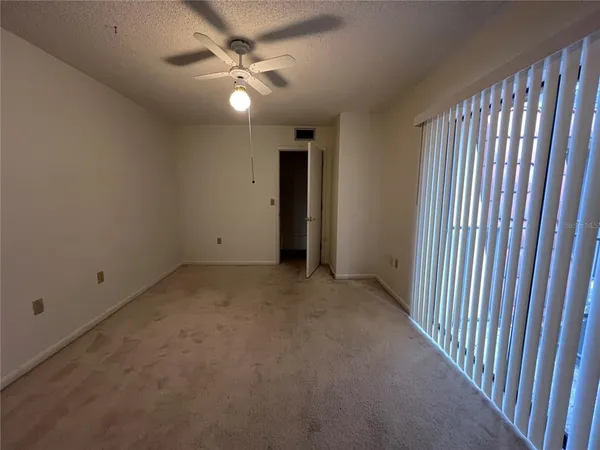 an empty room with a ceiling fan and carpet