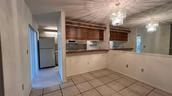 a view of a refrigerator in kitchen and an empty room