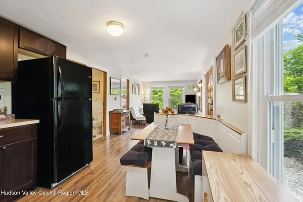 a living room with furniture two large window and a refrigerator