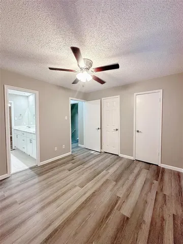 a view of an empty room with wooden floor and a ceiling fan