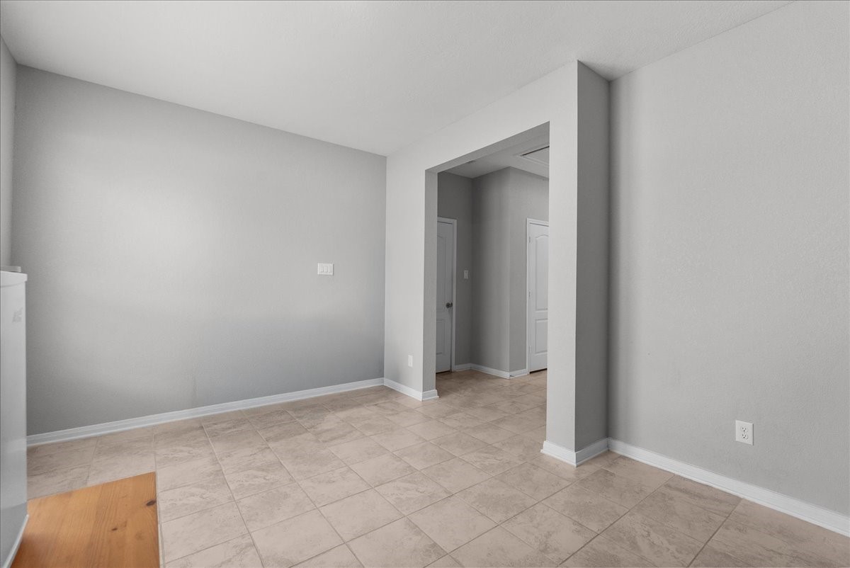 2320 Rosemary Street Rosenberg, TX 77469 - Photo 31 of 40 This photo shows a bright, open room with neutral gray walls and light-colored tile flooring. The space features a doorway leading to another area, creating a seamless flow and potential for flexible use.