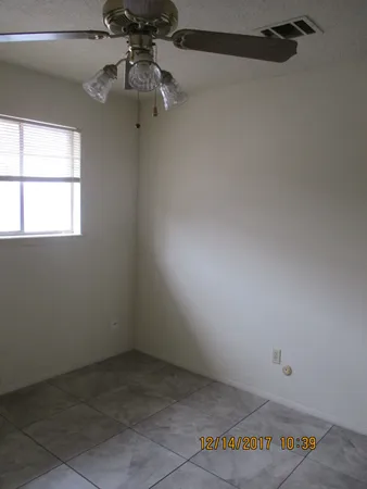 an empty room with a ceiling fan and window