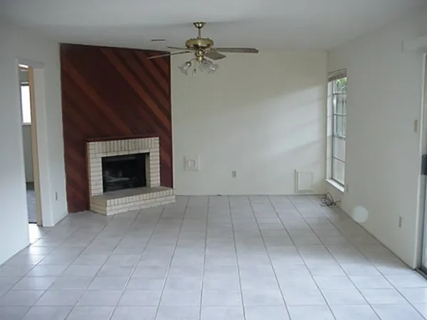 an empty room with a fireplace and a chandelier fan