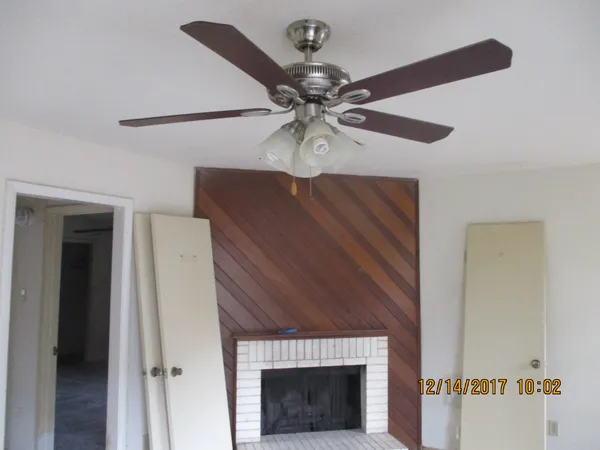 a view of a livingroom with a fireplace a chandelier fan and wooden floor