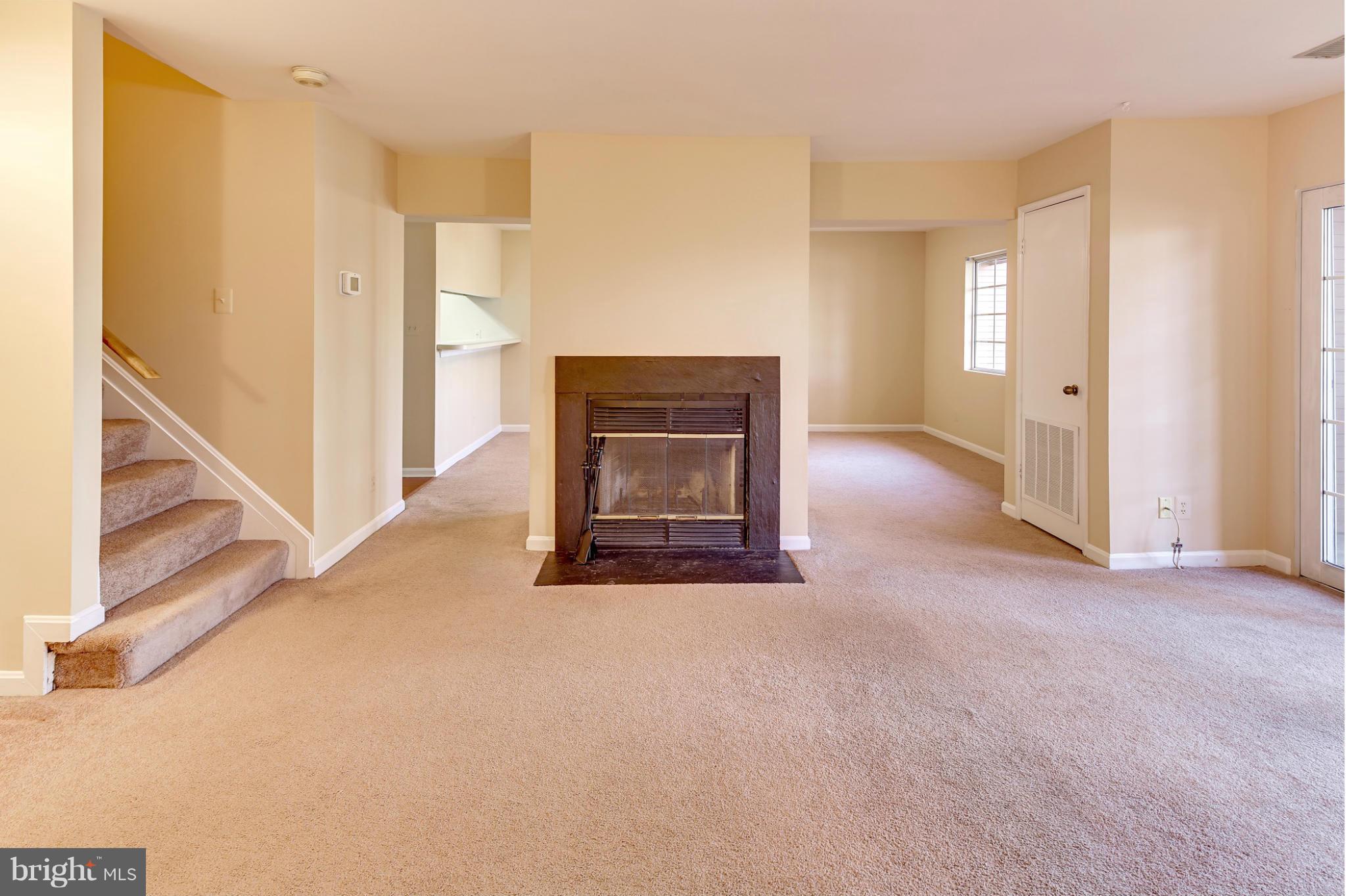 a view of an empty room with a fireplace and a window