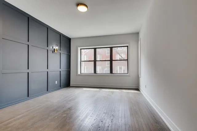 a view of an empty room with a window and wooden floor