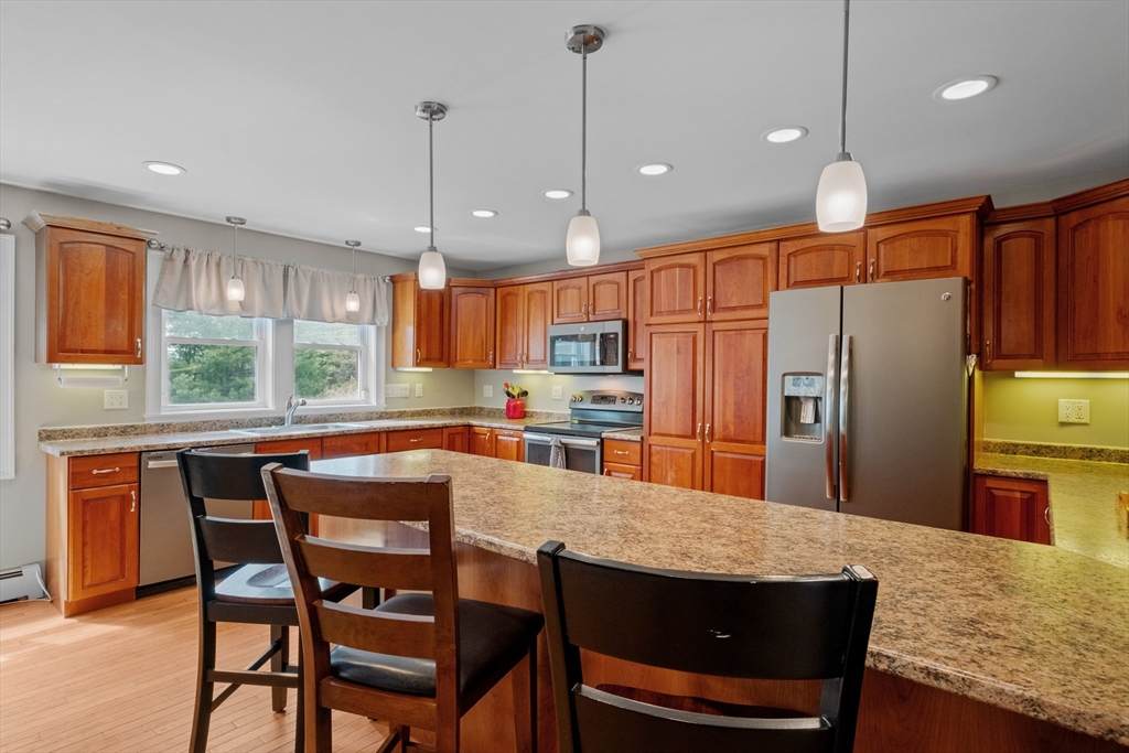 275 Lucas Road Manchester, NH 03109 - Photo 12 of 39 a kitchen with granite countertop a table chairs microwave and refrigerator