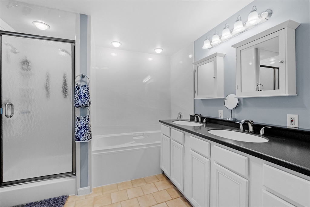 275 Lucas Road Manchester, NH 03109 - Photo 21 of 39 a bathroom with a double vanity sink a mirror and a bathtub