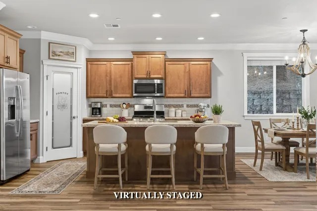 a kitchen with stainless steel appliances granite countertop a dining table chairs refrigerator and sink