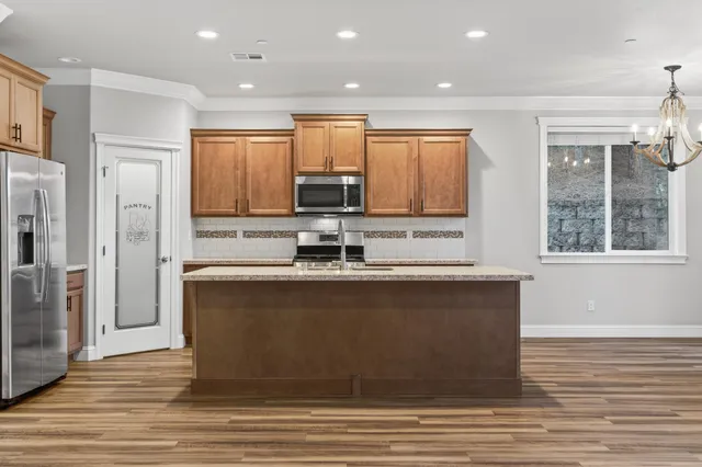 a large kitchen with stainless steel appliances granite countertop a stove a sink and a refrigerator