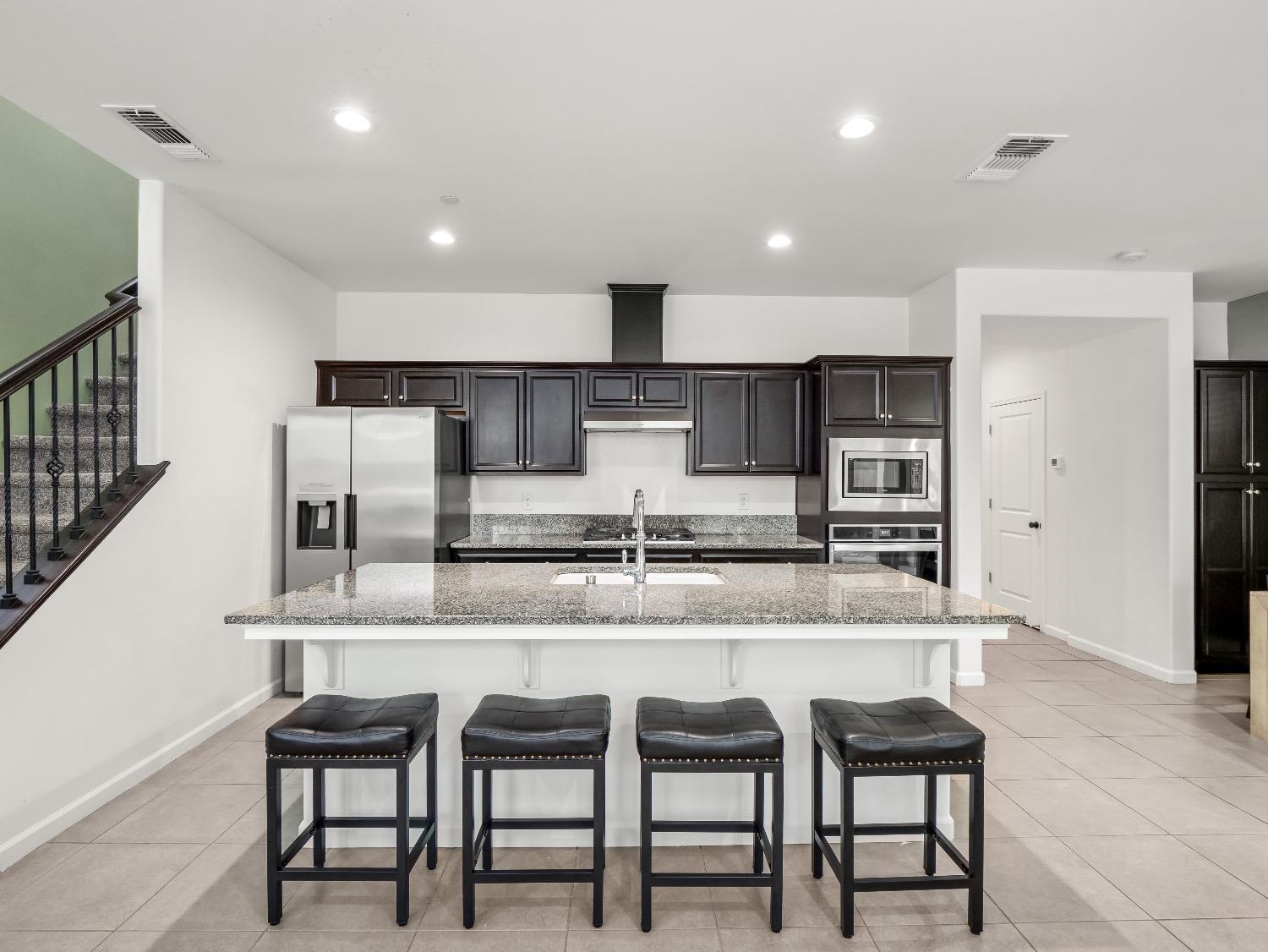 867 Fir Street Madera, CA 93636 - Photo 11 of 39 a kitchen with stainless steel appliances kitchen island granite countertop a table and chairs in it
