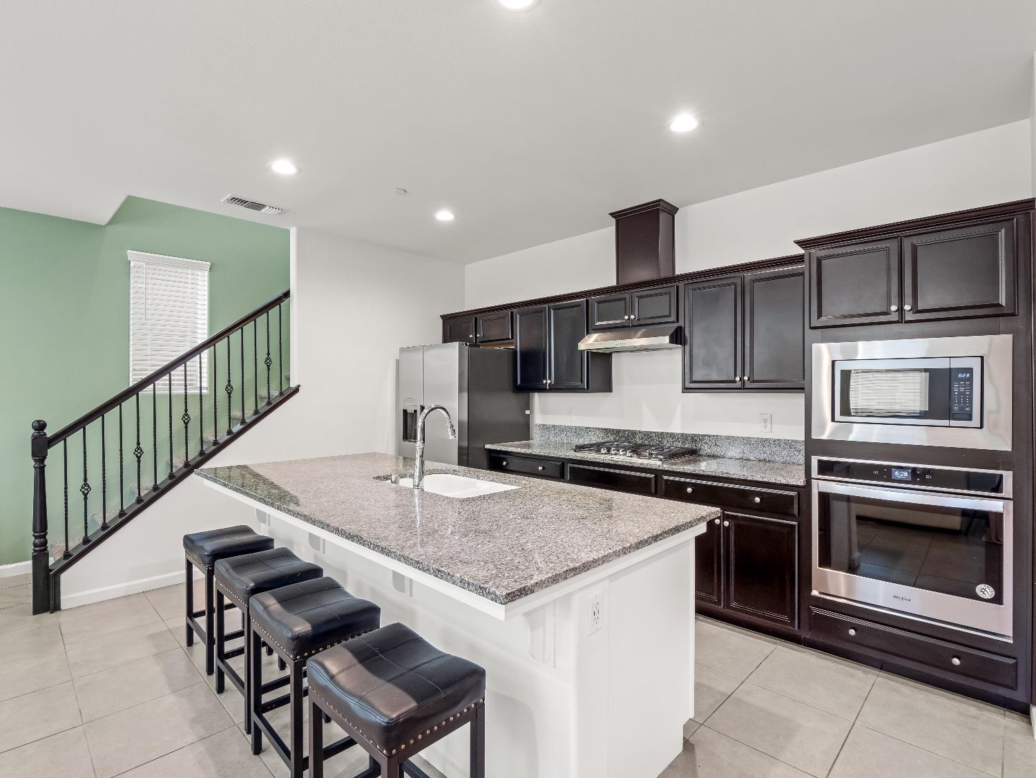 867 Fir Street Madera, CA 93636 - Photo 12 of 39 a kitchen with stainless steel appliances granite countertop a stove a sink and a microwave