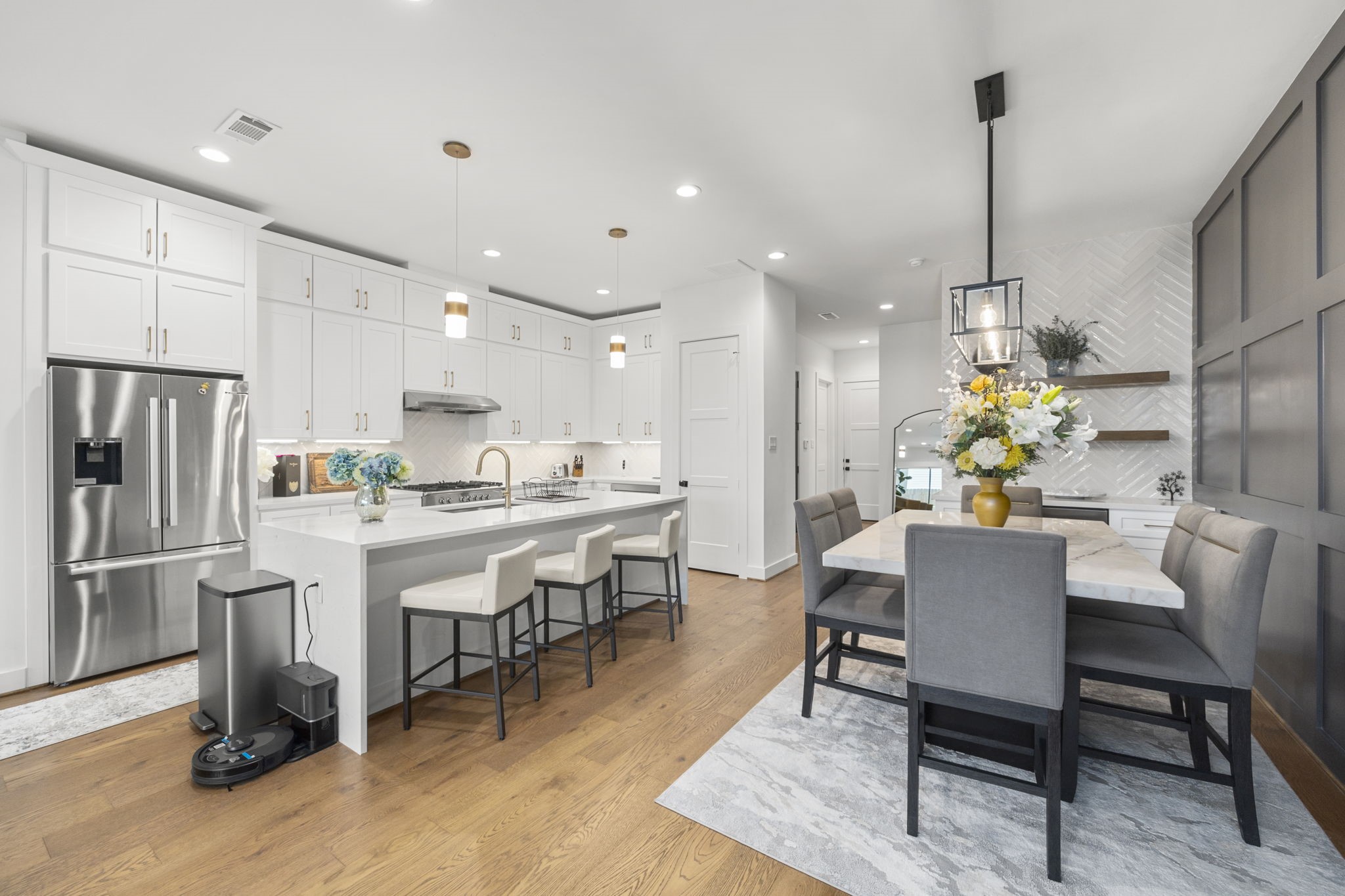 2411 Hazard Street Houston, TX 77019 - Photo 2 of 46 This bright and airy kitchen and dining space offers a perfect blend of functionality and style. The oversized island with seating for three is ideal for casual meals or meal prep, while the adjacent dining area is anchored by a modern chandelier and features a chic accent wall and custom shelving. The combination of sleek appliances and designer finishes elevates the heart of this home, making it perfect for both everyday living and entertaining.