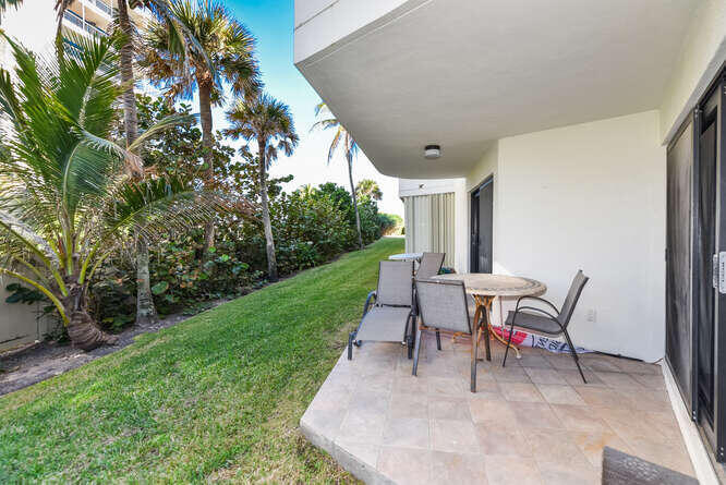 420 Celestial Way, Unit 101 Juno Beach, FL 33408 - Photo 27 of 37 a view of a backyard with table and chairs with a yard and plants