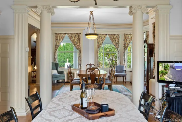 a dining room with wooden floor a chandelier a wooden table and chairs