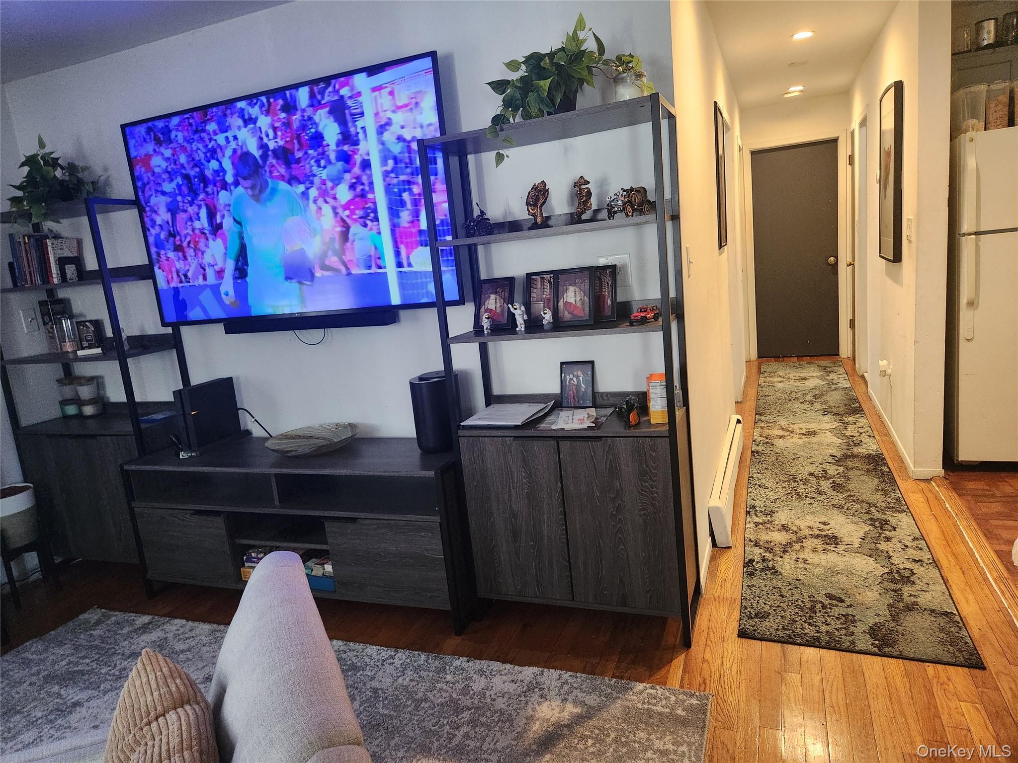 142-34 Bascom Avenue Queens, NY 11436 - Photo 9 of 21 Living area with light wood-style flooring and a baseboard heating unit