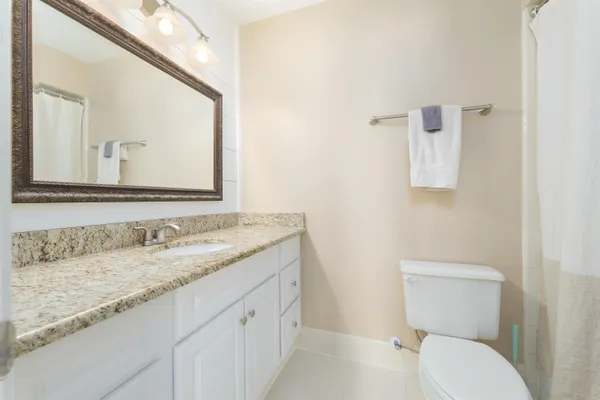 a bathroom with a granite countertop toilet sink and mirror
