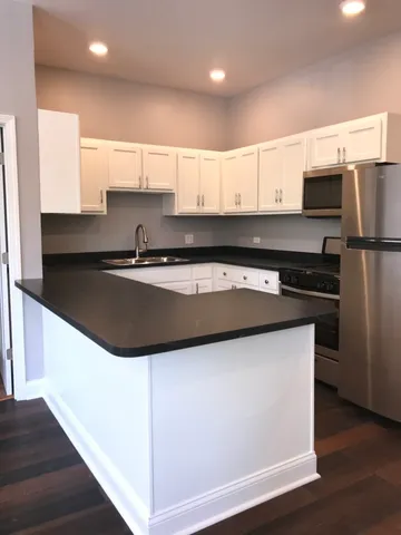 a kitchen with a sink a refrigerator and white cabinets