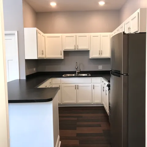 a kitchen with granite countertop a refrigerator and cabinets