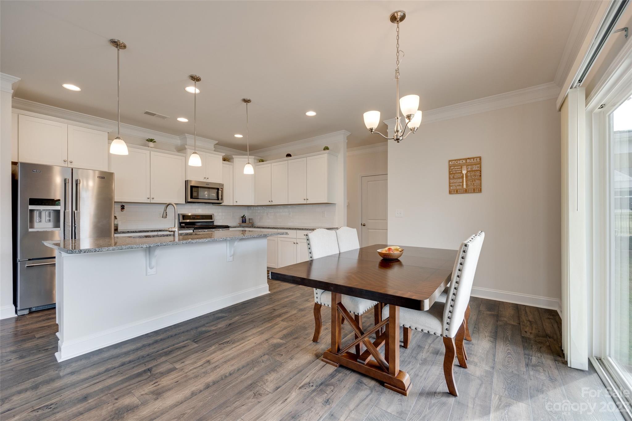 8013 Oakmere Road Waxhaw, NC 28173 - Photo 10 of 30 a kitchen with stainless steel appliances kitchen island granite countertop a dining table chairs and stove top oven