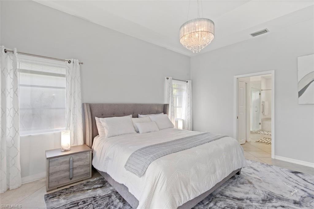 11774 Longshore Way West Naples, FL 34119 - Photo 20 of 35 a bedroom with a bed and a chandelier