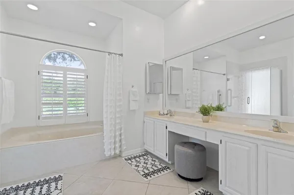 a spacious bathroom with a granite countertop sink a mirror a bathtub and next to a window