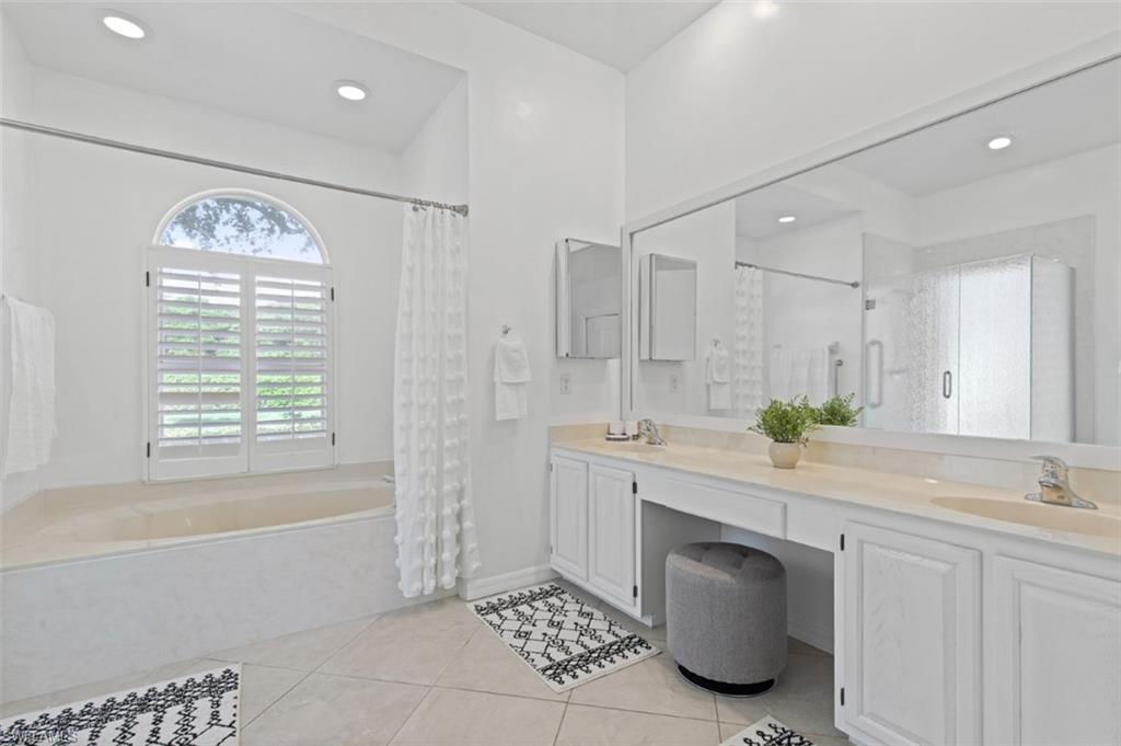 11774 Longshore Way West Naples, FL 34119 - Photo 23 of 35 a spacious bathroom with a granite countertop sink a mirror a bathtub and next to a window