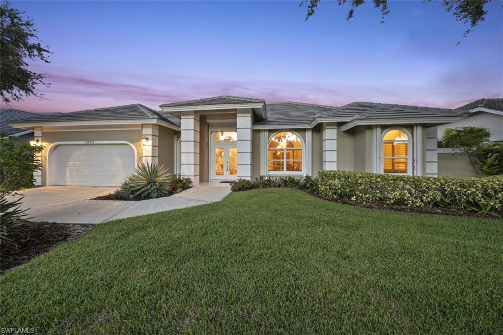 11774 Longshore Way West Naples, FL 34119 - Photo 3 of 35 a front view of a house with a garden and yard