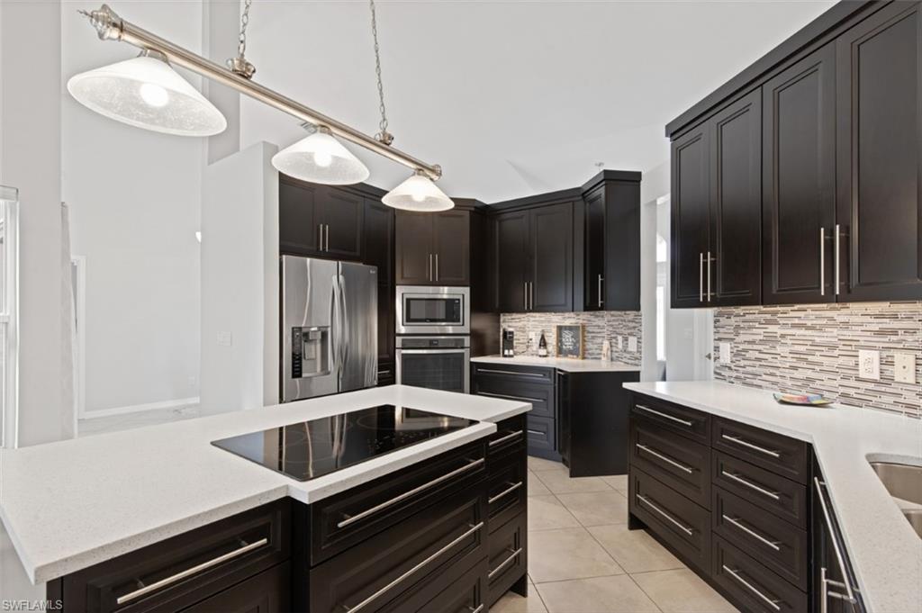 11774 Longshore Way West Naples, FL 34119 - Photo 8 of 35 a kitchen with stainless steel appliances kitchen island granite countertop a stove refrigerator and cabinets