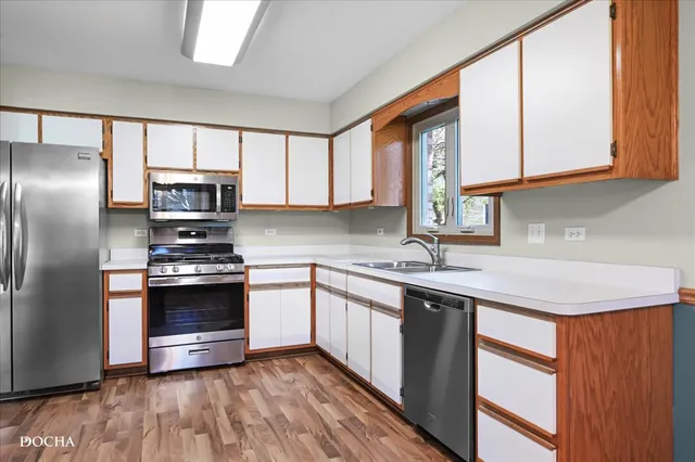 a kitchen with stainless steel appliances granite countertop a sink a stove a refrigerator cabinets and a window