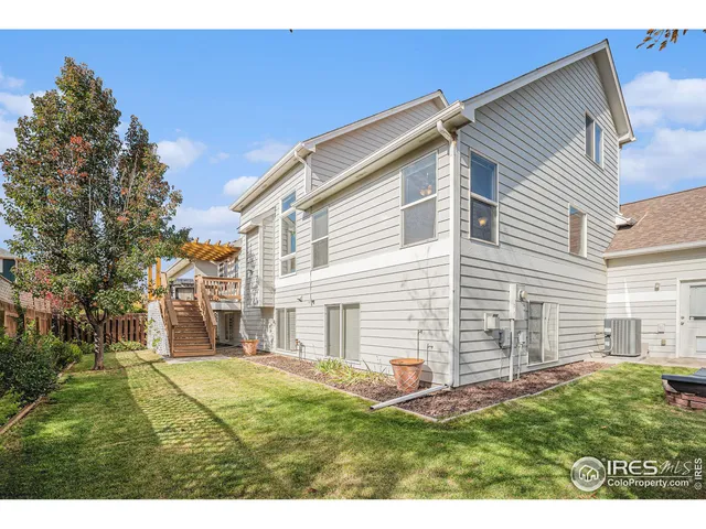 a backyard of a white house with potted plants and a large tree