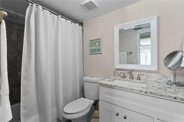 a bathroom with a granite countertop sink toilet and a mirror