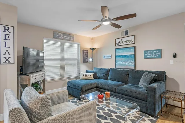 a living room with furniture a ceiling fan and a flat screen tv