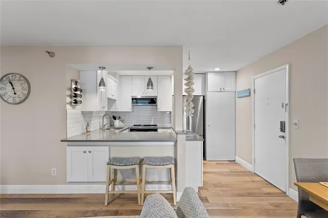 a kitchen with granite countertop a table chairs refrigerator and cabinets