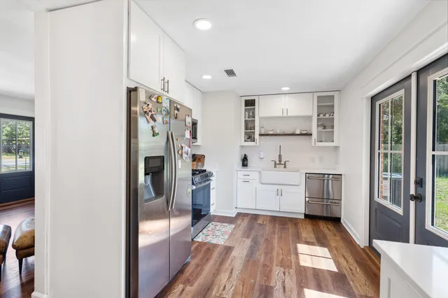 a large white kitchen with a sink stainless steel appliances and cabinets