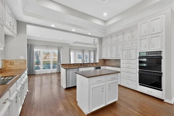a kitchen with granite countertop kitchen island wooden floor and stainless steel appliances