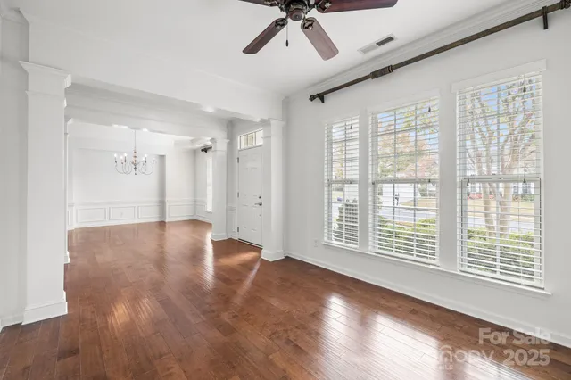 a view of an empty room with a window and wooden floor