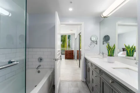 a spacious en suite bathroom with a granite countertop tub sink and mirror