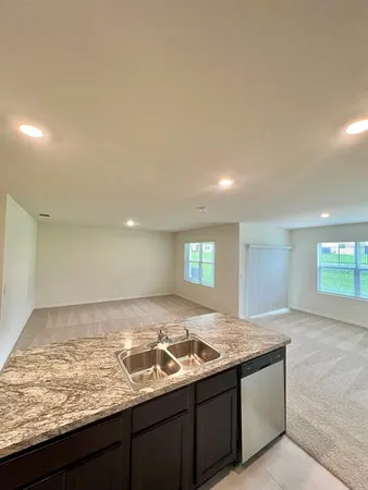 a view of a kitchen island a sink wooden floor and a living room