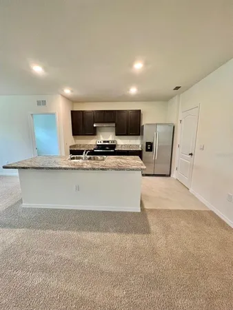 a large white kitchen with stainless steel appliances a large counter top a stove a microwave a sink and a refrigerator