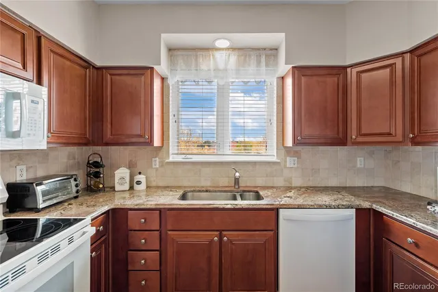 a kitchen with stainless steel appliances granite countertop a sink dishwasher stove and cabinets with wooden floor